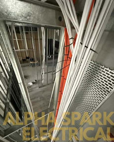 White and orange cables run and secured through metal wall studs