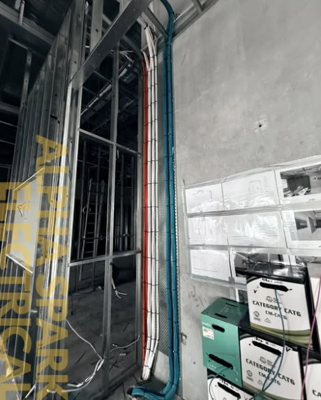 Bundled red, white and blue Cat6 data cabling run along a concrete wall